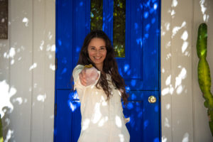 Ilona Barnhart at Four Moons Spa in Encinitas California with blue door and a rose quartz in hand